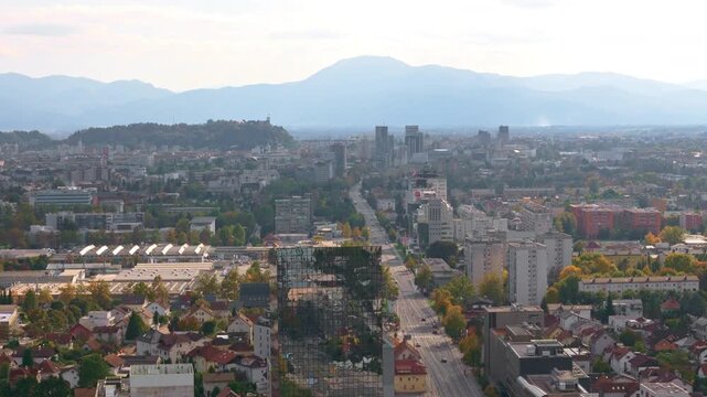The aerial view shows Ljubljana, the capital city of Slovenia, with buildings and hills on a clear day.