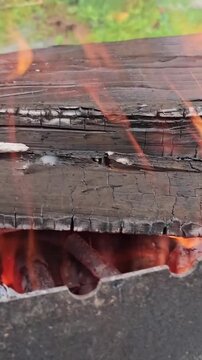 Fire burns through a log showing smoke and bright flames in a natural setting