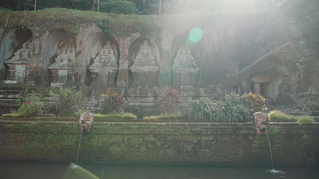 Ancient stone shrines and rock carvings at Gunung Kawi Temple surrounded by lush tropical vegetation in Tampaksiring Bali Indonesia