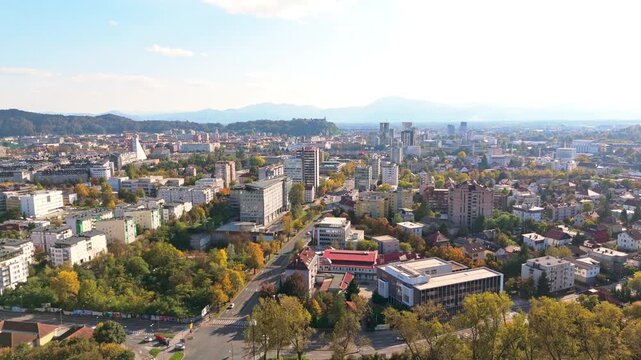 Urban landscape of Ljubljana, Slovenia with buildings and hills under a sunny sky.