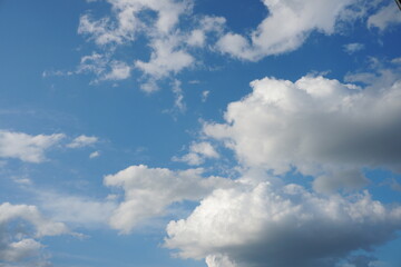Obraz premium White fluffy clouds in the sky. Blue sky and cloud cover on a sunny summer day. Empty background, copy space