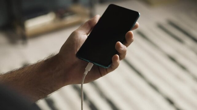 Slow motion close up of man hand plugging and unplugging USB C cable into smartphone
