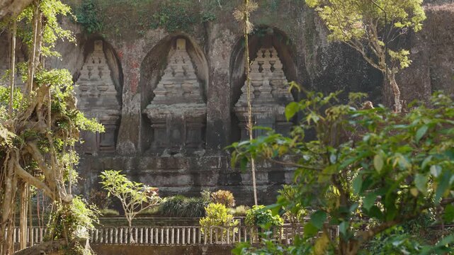 Ancient stone shrines and rock carvings at Gunung Kawi Temple surrounded by lush tropical vegetation in Tampaksiring Bali Indonesia