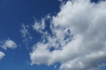 Obraz premium White fluffy clouds in the sky. Blue sky and cloud cover on a sunny summer day. Empty background, copy space