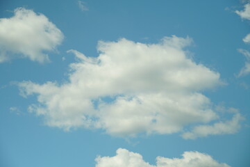 Obraz premium White fluffy clouds in the sky. Blue sky and cloud cover on a sunny summer day. Empty background, copy space