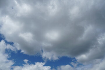 Obraz premium White fluffy clouds in the sky. Blue sky and cloud cover on a sunny summer day. Empty background, copy space