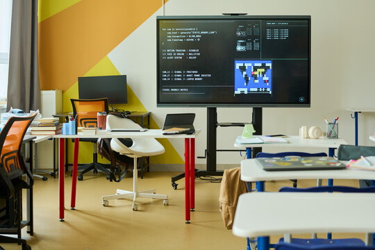 Empty modern classroom showing interactive digital whiteboard displaying computer programming code. Perfect for promoting STEM education, coding bootcamps, and school technology integration