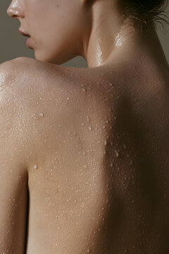 Water droplets glisten on wet shoulder skin near jawline macro