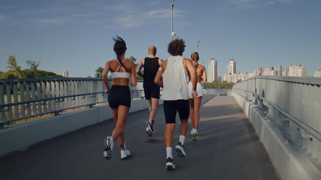Fitness group runs together across modern pedestrian bridge