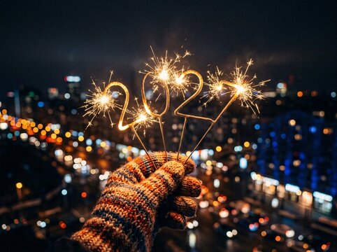 Hand holding sparkling 2027 light numbers against blurred night city street