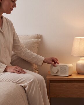 Woman Adjusts White Noise Machine During Relaxing Bedtime Routine