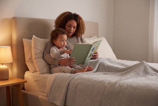 Caregiver and Young Child Read Picture Book Together at Bedtime