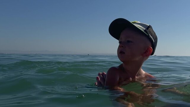 Curious boy swimming in the sea supported by his father. 4k