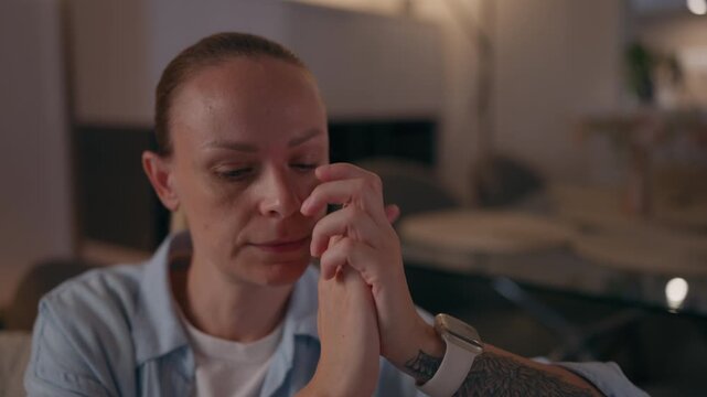 Sad woman sitting alone at home and looking distressed, representing family problems, relationship difficulties, emotional conflict and personal struggles.