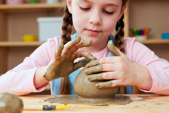 Close up of Caucasian child shaping clay with hands during pottery lesson, developing creativity and fine motor skills. Useful for education, art class, child development