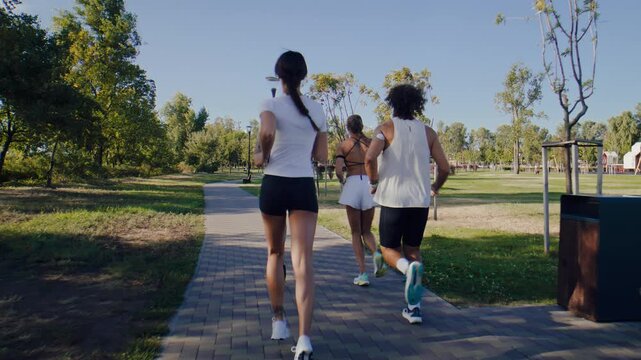 Runners continue group workout along green park pathway