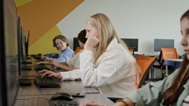 Caucasian teenagers sitting in computer lab, typing on keyboards and learning during IT class. Clip is perfect for marketing school programs, STEM education, and digital literacy courses