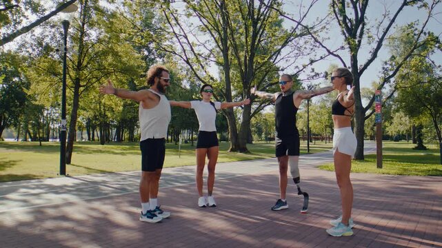 Fitness group stretches arms together during sunny park warmup
