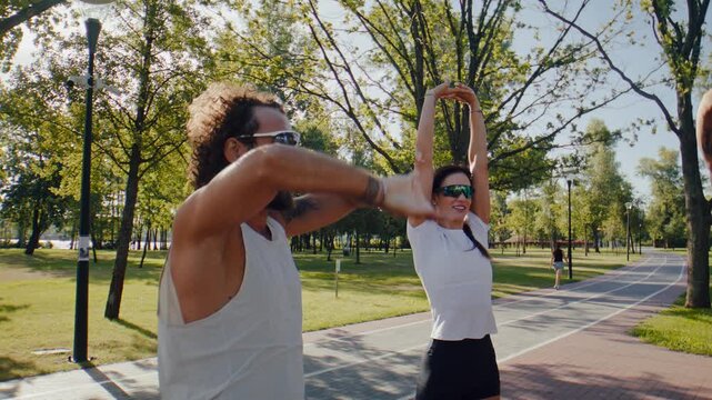 Runners raise arms overhead during outdoor warmup in green park
