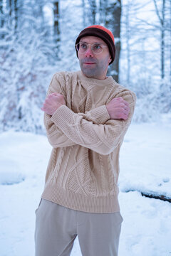 Young man in beanie and sweater shivers in snowy forest, looking lost and cold, survival struggle, winter danger, hypothermia risk, urgency rescue, Frozen and alone, freezing outdoors, lost person