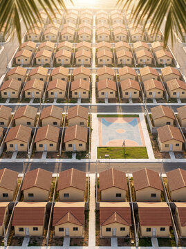 Aerial view of identical residential suburban houses in a planned community with a sports court at golden hour