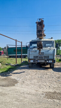 Gray Kamaz-53212 truck crane with the boom raised against a blue sky near Tbilisi; Russian crane truck; construction vehicle; Tbilisi region, Georgia