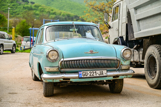 blue historic GAZ-21 Volga classic car from the 1950s, in a parking lot in front of green hills near Shignaghi; Soviet classic cars, Georgia