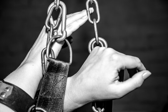Black and white image shows hands bound by heavy metal chains