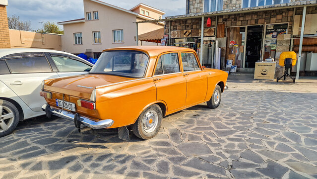 An orange Moskvich-2140 classic car parked on cobblestones in front of a building in Sighnaghi; a historic Soviet sedan with a Georgian license plate, Kakheti, Georgia 13.04.2025