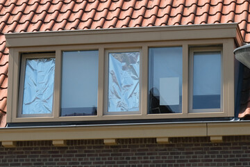 Homeowner uses aluminum foil on windows to block heat during heat wave, DYI during heat wave.   © Pelle