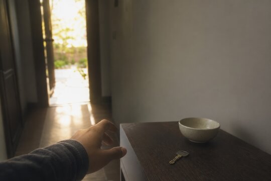 First person view of hand reaching for keys on entryway table