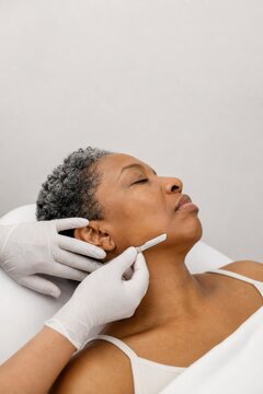 Mature Black woman receiving dermaplaning treatment at a spa