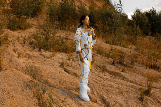 Terraformed planet colonization concept with woman astronaut standing on a red hillside