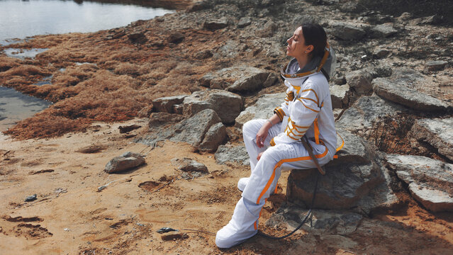 Peaceful moment of a female astronaut warming her face in the light of an alien sun