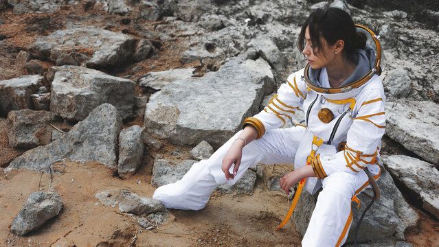 Geological survey break with an astronaut seated among grey boulders and red sand