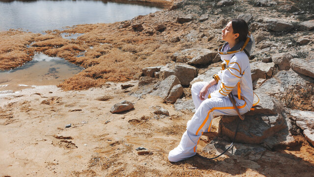 Homesick astronaut on the rocky shore of a lifeless planet with copy space