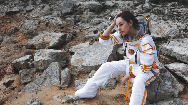 Exhausted woman astronaut holding her head during a difficult planetary mission