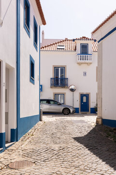 picturesque traditional blue and white homes with orange tiled roofs on cobblestone streets in Ericeira, Portugal