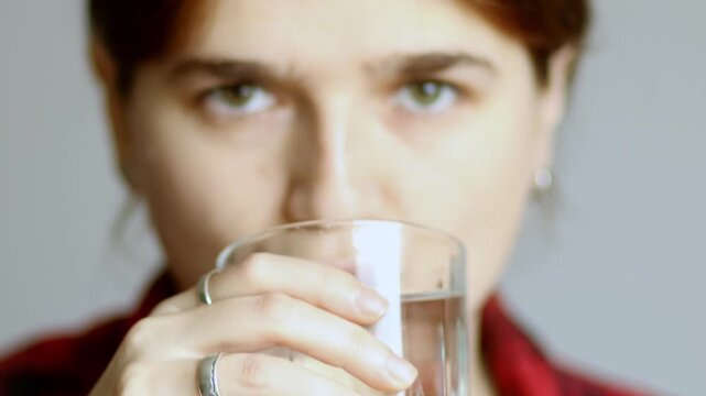 A woman taking a pill with a glass of water, focusing on healthcare, treatment, cold sore, and herpes remedy. a person taking vitamins and prescription drugs during illness