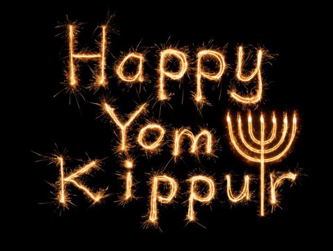 Happy yom kippur spark text with menorah design on dark background
