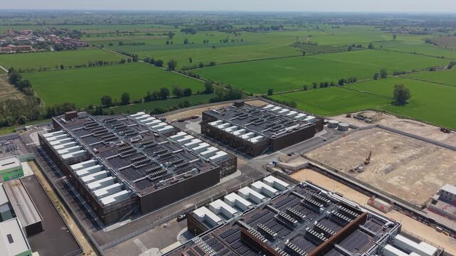 Aerial view of a multi-building data center campus in Italy, featuring rooftop cooling units, backup generators and solar panels.