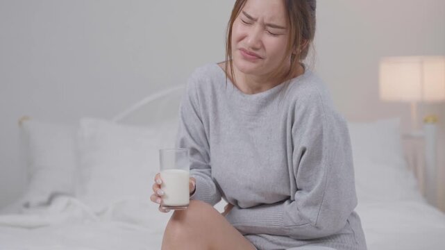 Lactose intolerance concept, young woman suffers stomach pain after drinking milk while sitting at home, lactose, intolerance, stomachache, milk, digestion