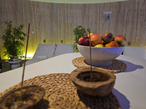 Decorative bowl with apples on table with incense holders