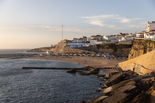 golden hour sunset wide shot of Ericeira coast in Portugal with cliffs, ocean, and buildings