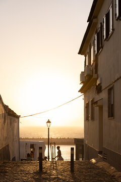 view from narrow residential cobblestone street in Ericeira, Portugal looking towards ocean during golden hour