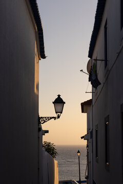 view from narrow residential cobblestone street in Ericeira, Portugal looking towards ocean during golden hour