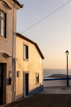 view from narrow residential cobblestone street in Ericeira, Portugal looking towards ocean during golden hour