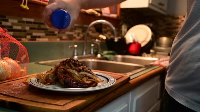 Fryed pork chop, men cooking, real people, authentic home cooking video, fresh meal prep, steaming pork chop onions served on a white plate, 