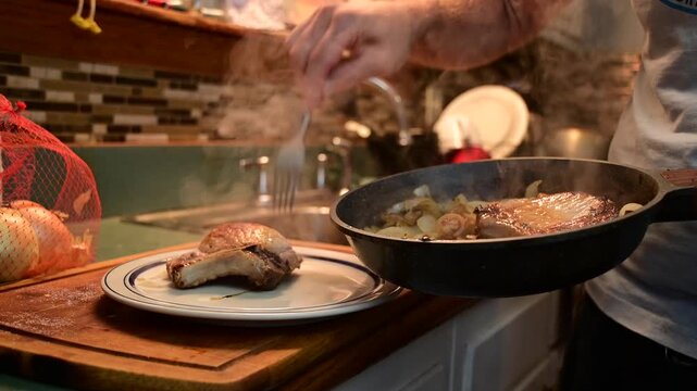 Fryed pork chop, men cooking, real people, authentic home cooking video, fresh meal prep, steaming pork chop onions served on a white plate, 