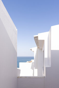 white architectural house by the sea with orange tiled roof with blue ocean in the background, minimal, negative space
